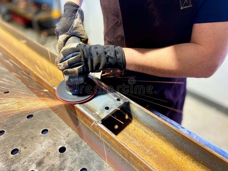 Worker grinding metal surface with angle grinder sparks